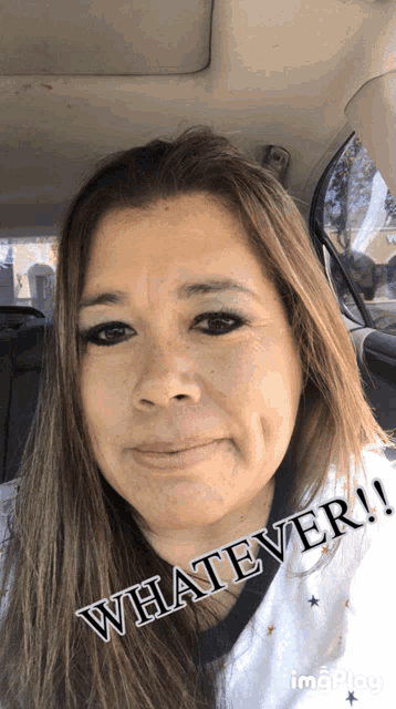 a woman sitting in a car with the word whatever written on her face