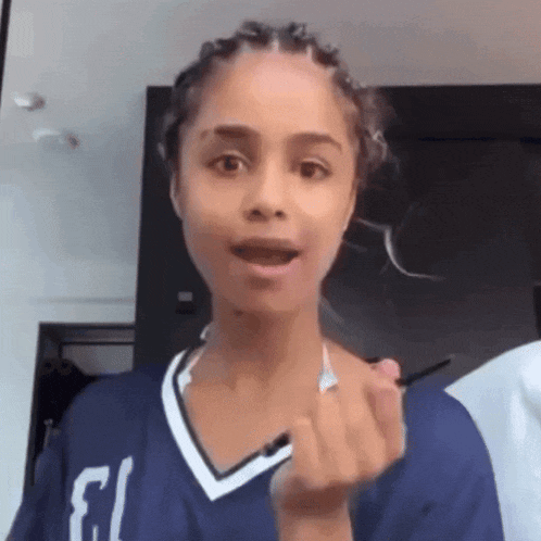 a woman wearing a blue shirt with the number 13 on it is making a funny face .