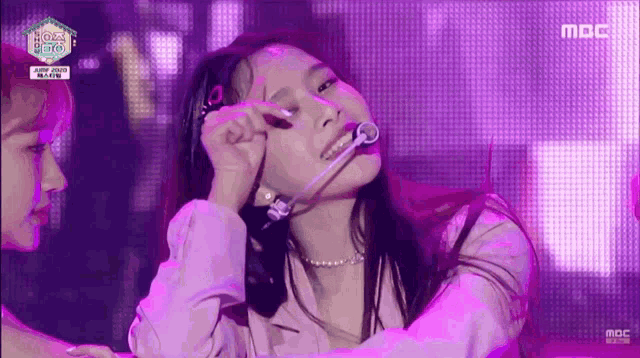 a woman with a microphone in her mouth is on a stage with a mbc logo in the background