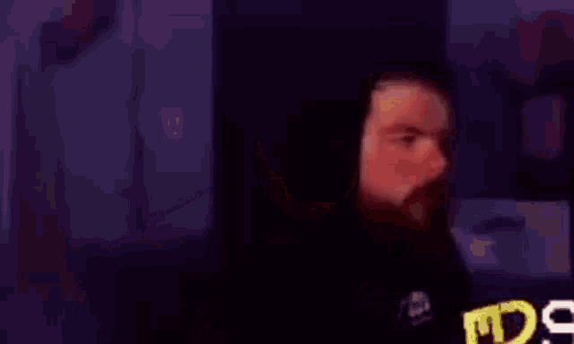a man with a beard is holding a remote control in his hand and making a funny face .
