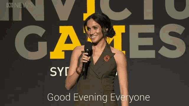 a woman holding a microphone in front of a sign that says invicto games