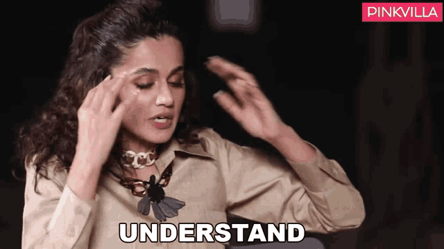a woman wearing a necklace and a tan shirt is saying " understand "