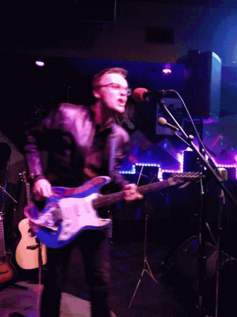 a man singing into a microphone while playing a guitar that says poison