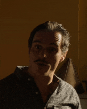a man with a mustache is standing in front of a boat