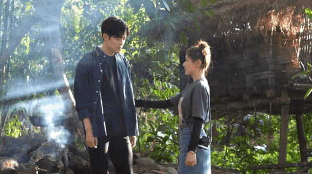 a man and woman are standing next to each other in the woods