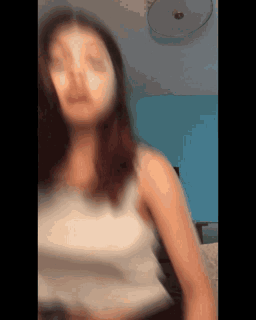 a blurry picture of a woman wearing a white tank top .