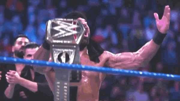 a man in a wrestling ring holding a wwe title