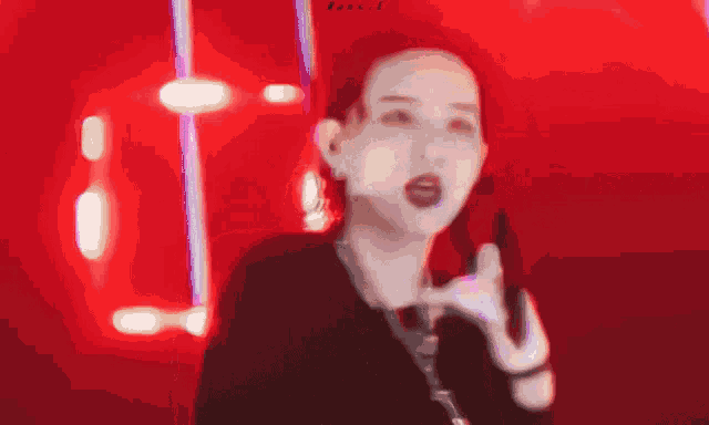 a blurry picture of a woman making a peace sign in front of a red background