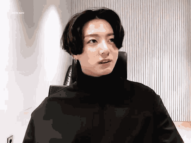 a young man is wearing a black turtleneck sweater and earrings .
