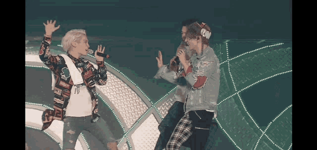 two men singing into microphones with one wearing a jacket that says supreme on it