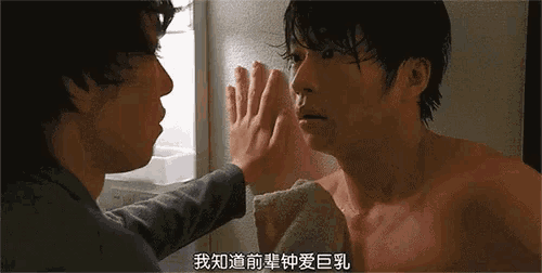 a man without a shirt is touching another man 's face in a foreign language
