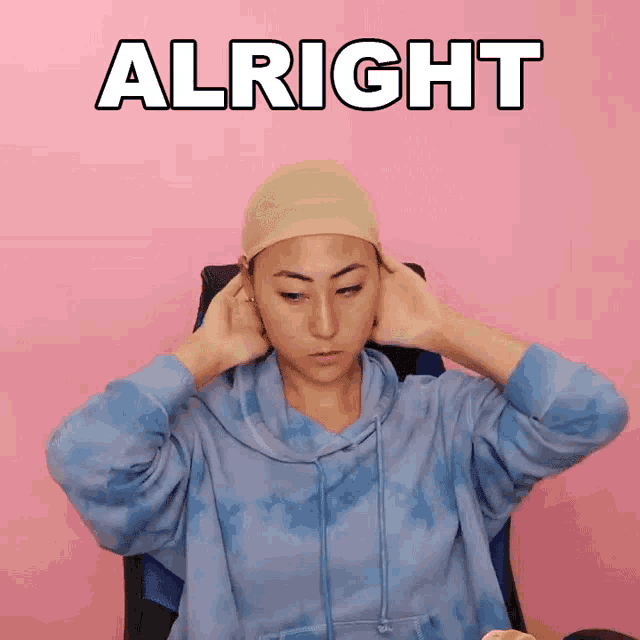 a woman in a blue tie dye hoodie covering her ears with her hands and the word alright above her
