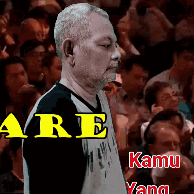 a man stands in front of a crowd with the words are kamu yang visible