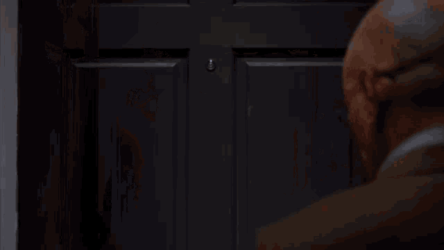a man with glasses is looking through a door .