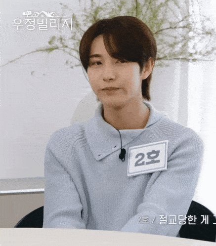 a young man wearing a blue sweater has a name tag that says 2 on it