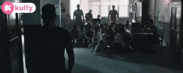 a man is standing in front of a crowd of people sitting on the floor .