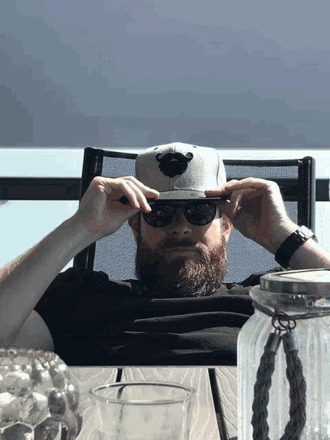 a man with a beard wearing sunglasses and a baseball cap