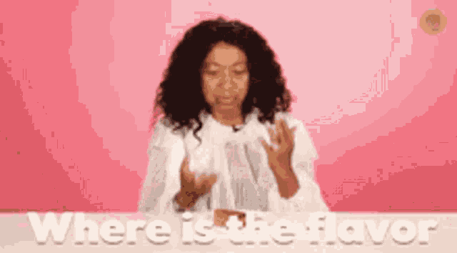 a woman with curly hair is sitting at a table with the words where is the flavor written above her