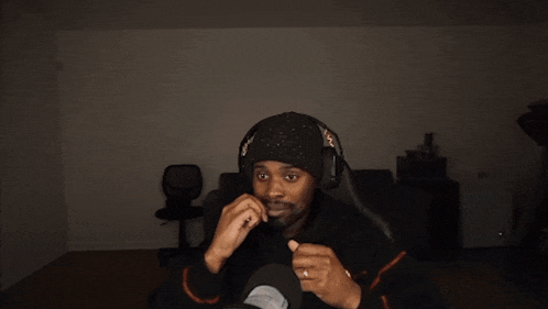 a man wearing headphones and a hat is holding a toothpick in his mouth in front of absolute cinema