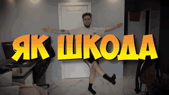a man with his arms outstretched stands in front of a sign that says " як шкода "