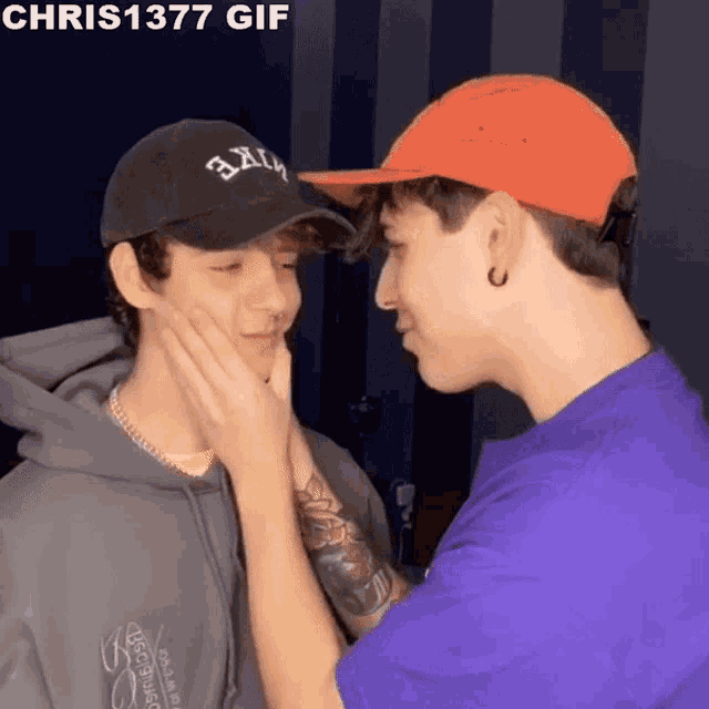a man in an orange hat touches another man 's face