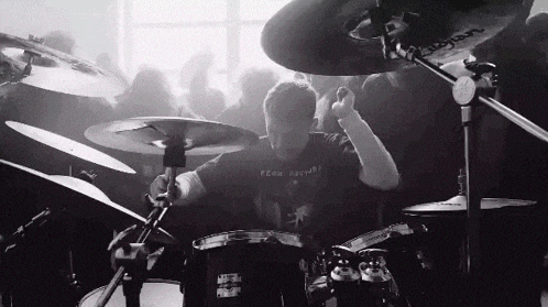 a man playing drums with a shirt that says " time travel " on it