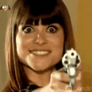 a woman is holding a gun in her hand and smiling .