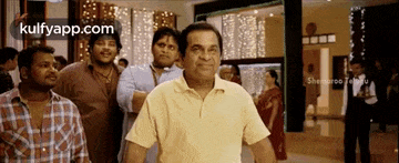 a man in a yellow shirt is standing in front of a group of people .