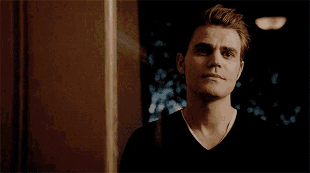 a man in a black shirt is looking at the camera