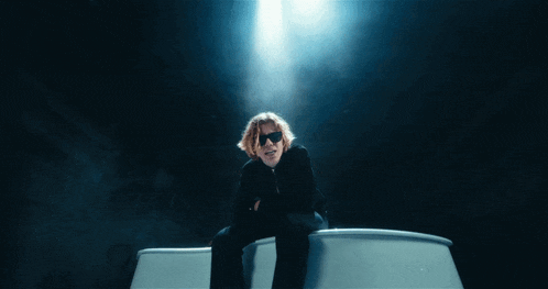 a man wearing sunglasses is sitting on a boat in the dark