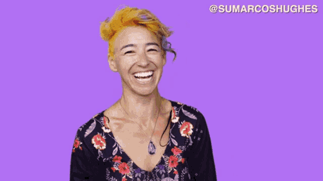 a woman with orange hair is laughing in front of a purple background with @sumarcoshughes written on it