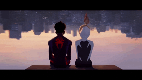 a man and a woman are sitting on a ledge with a city in the background