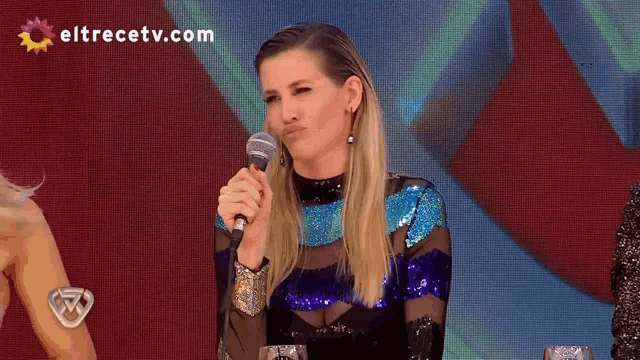 a woman speaking into a shure microphone with eltrecetv.com in the corner