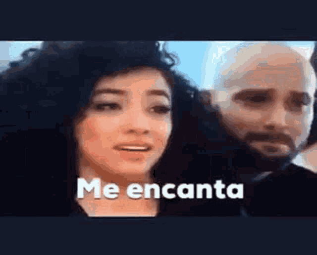 a woman with curly hair is standing next to a man with a beard and says `` me encanta '' .