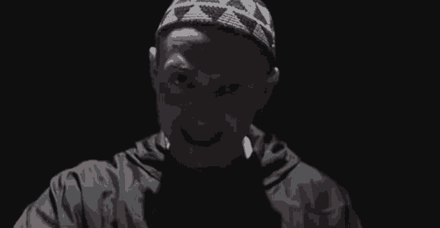 a man wearing a headband and a black jacket is making a funny face .