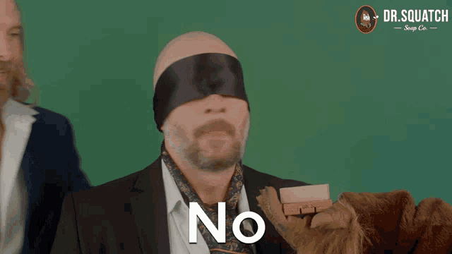 a man in a suit and tie is blindfolded and the word no is on his face