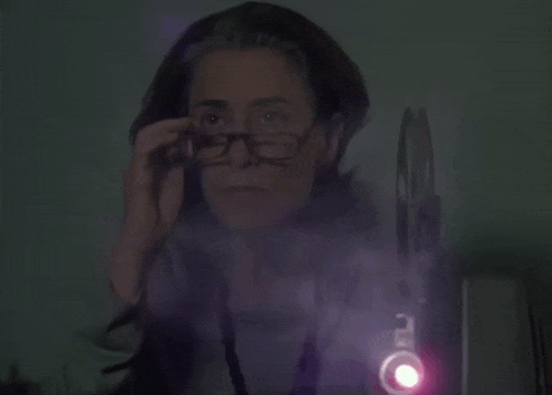 a woman is sitting in front of a projector with a purple light shining on her face .