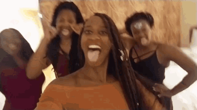 a woman is sticking her tongue out while taking a selfie with her friends .