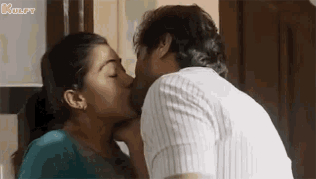 a man and a woman are kissing each other in a kitchen .