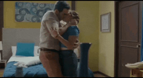 a man and a woman are kissing in a hotel room .