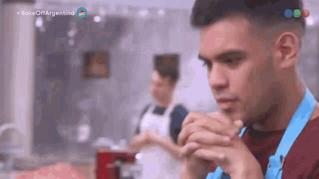 a man wearing a blue apron is looking at something in a kitchen