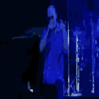 a man in a blue shirt singing into a microphone on a stage