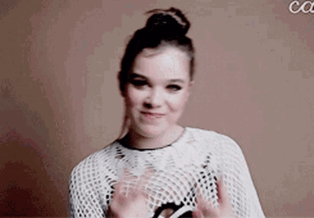 a woman wearing a white sweater is giving a thumbs up .