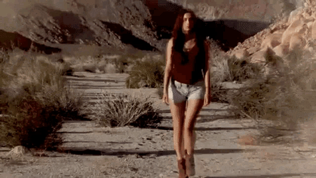 a woman in shorts is walking through a desert .