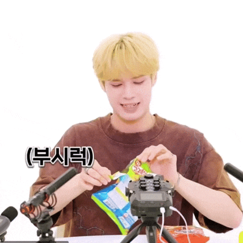 a young man is sitting in front of a microphone and holding a bag of food