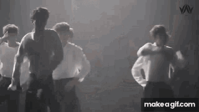 a group of men are dancing together on a stage in a dark room .