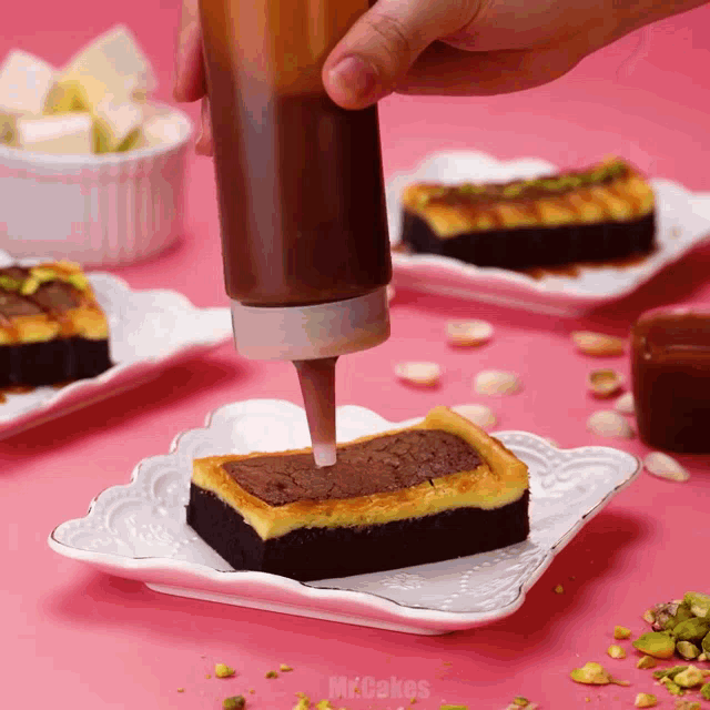 a person is pouring chocolate sauce on a piece of cake on a white plate