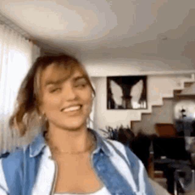 a woman in a blue and white striped shirt is smiling and looking at the camera .