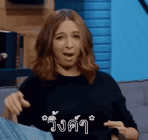 a woman is sitting on a couch with her mouth open in a foreign language