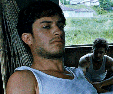 a man in a white tank top sits in a chair